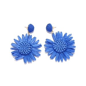 Vue détaillée des boucles d'oreilles tournesol en raphia bleu roi avec texture tissée