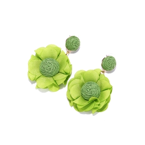 Detail of handcrafted green chiffon flower earrings with woven raffia and layered petals