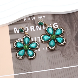 Macro detail of vintage floral earrings with green teardrop stones and white crystals