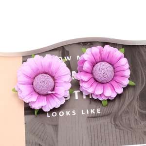 Detail shot of handcrafted purple fabric flower earrings with green leaf accents