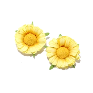 Detailed view of handmade yellow fabric daisy earrings with layered petals and green leaves