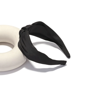 Detailed view of black satin knot headband with wide side design on white display