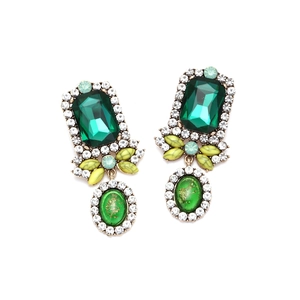 Detailed close-up of vintage palace style gold earrings with emerald green and yellow crystals