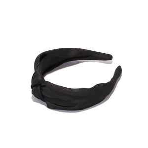 Detail of elegant black knotted satin headband with a smooth silk-like texture