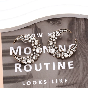 Vintage gold crescent moon earrings with rhinestones on fashion magazine background