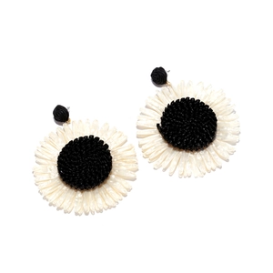Macro detail of hand-woven raffia sunflower earrings with black and white texture