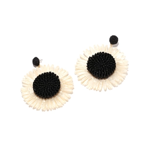 Detail of handmade raffia sunflower earrings featuring black beaded core and white petals