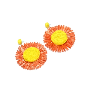 Macro view of sunflower earrings made from handmade woven raffia in vibrant orange and yellow