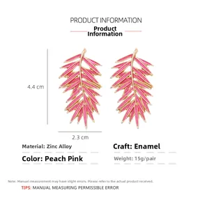 Détail macro de boucles d'oreilles feuilles de palmier en émail rose dimensions 4,4x2,3cm