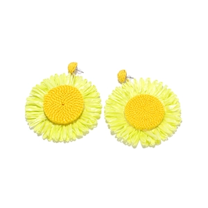Macro detail of hand-woven raffia sunflower earrings with yellow fiber texture