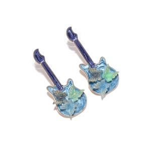 Macro shot of blue guitar earrings with colorful butterfly details and enamel finish