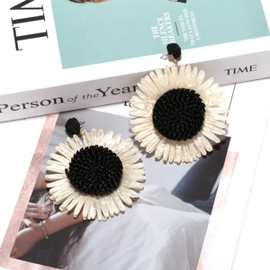 Close-up of bohemian woven raffia sunflower earrings with intricate petal texture