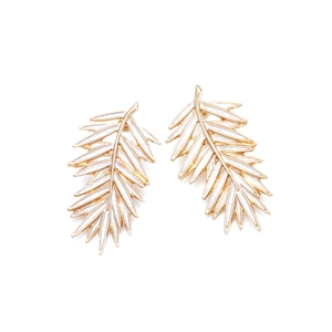 Détail de boucles d'oreilles feuille dorées avec émail blanc et fermoirs à poussette