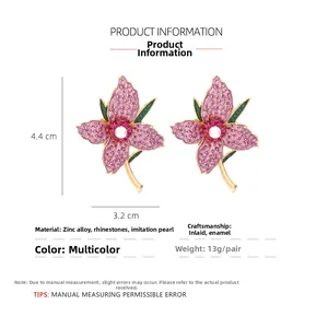 Detail view of purple flower earrings with faux pearl center and rhinestone accents