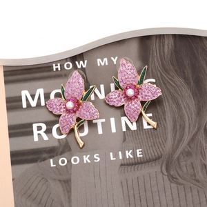 Elegant floral stud earrings with purple enamel petals, faux pearl center, and gold accents
