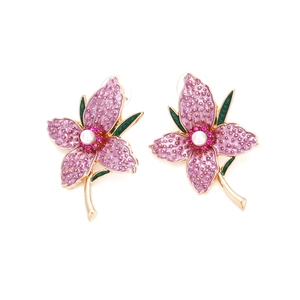 Detail of flower stud earrings featuring pink enamel petals and a central pearl accent