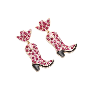 Détail des boucles d'oreilles bottes de cowboy ornées de cristaux roses sur base dorée