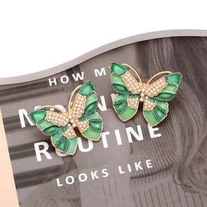 Retro butterfly stud earrings with green enamel and pearls on a fashion magazine