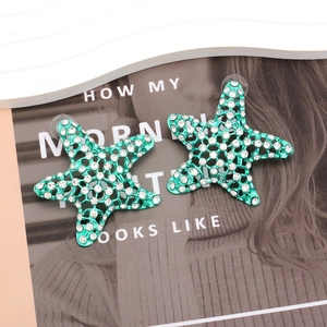 Fashionable green starfish earrings with sparkling rhinestones on a white tray