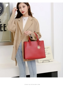 Detail of red quilted tote bag with golden maple leaf pendant shown by model