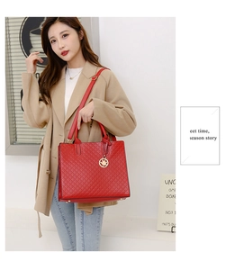 Detail of red quilted tote bag with gold maple leaf pendant worn with a beige trench coat