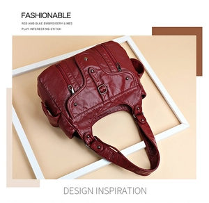 Detail view of red washed leather tote bag showing soft litchi texture and functional zippers