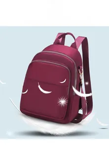 Vue détaillée du sac à dos en nylon bordeaux avec fermetures dorées et motifs de plumes