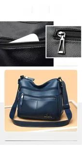 Detail view of navy blue textured leather crossbody bag with multiple zippers and silver logo