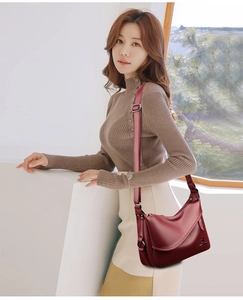 Detail view of burgundy pebble leather crossbody bag with metallic kangaroo logo