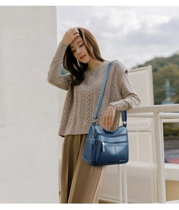 Detail of blue faux leather shoulder bag featuring multiple functional zippers and soft texture