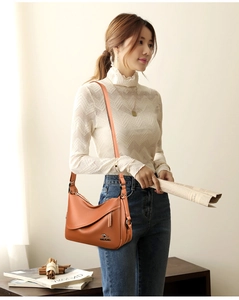Orange lychee grain leather crossbody bag with kangaroo logo shown on female model