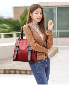 Detailed close-up of dark wine red leather tote bag with stylish grey buckles and straps