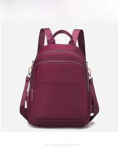 Vue de face d'un sac à dos en nylon bordeaux avec poches zippées et anneau en D en métal