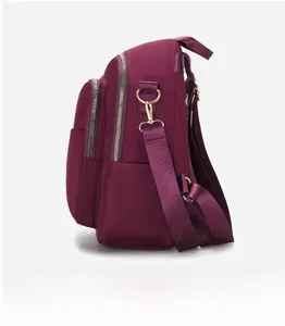 Vue latérale du sac à dos en nylon bordeaux avec fermetures éclair et boucles dorées