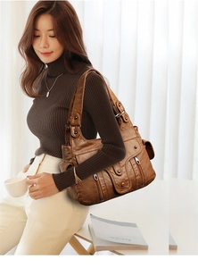 Detail view of brown washed leather tote with functional pockets and rivets on a model