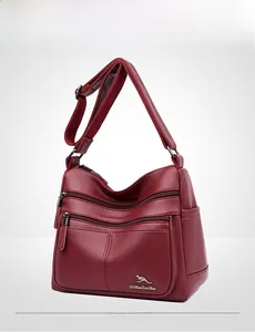 Detail of burgundy leather shoulder bag with lychee texture and silver zipper pockets