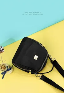 Dettaglio della borsa a conchiglia in nylon nero con doppia zip e placca dorata