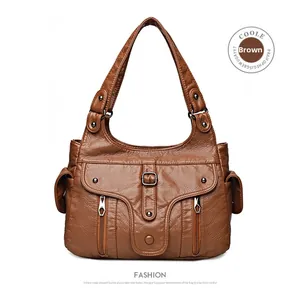 Detail of brown vintage PU leather handbag featuring dual zippers and metal buckles
