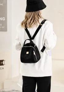 Semplice zaino nero in tessuto Oxford indossato da modella con cerniere dorate e logo metallo