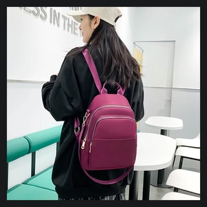 Détail du sac à dos en nylon magenta montrant la boucle dorée et les poches zippées