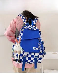 Blue and white checkered backpack with bunny and bear charms shown on a model