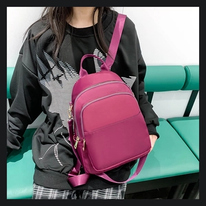 Détail d'un sac à dos en tissu Oxford magenta avec compartiments à fermetures éclair