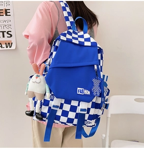 Close-up of blue checkerboard backpack with fashion label and cute plush keychains