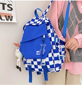 Detail of blue checkerboard canvas backpack with cute doll charms and adjustable straps