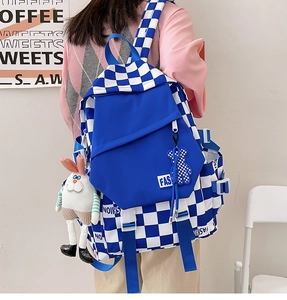 Detail of blue checkerboard backpack featuring plush bunny charm and large zip pocket