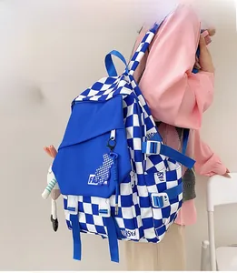 Close-up of checkerboard backpack with blue bear charm and side buckle detail