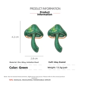 Detail of green enamel mushroom earrings with imitation pearls and gold-plated alloy trim