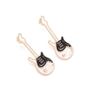 Boucles d'oreilles guitare avec émail noir et blanc et accents d'étoiles dorées sur fond blanc