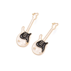 Détail macro de boucles d'oreilles guitare en émail avec étoiles dorées et fini noir