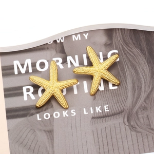 Golden starfish stud earrings with realistic textured finish on a fashion magazine